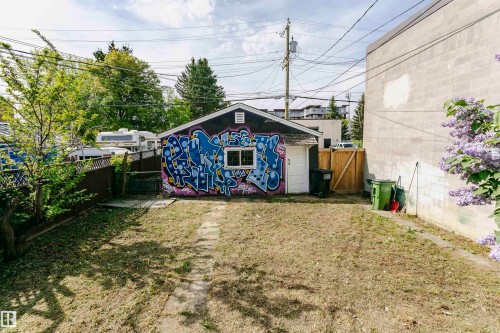 Detached garage building featuring a side entry door and a window, situated within a partially fenced yard - 10035 81 Avenue Nw, Edmonton, AB - Outdoor