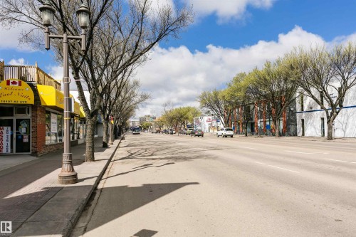 Street-level commercial buildings featuring brick facades, prominent signage, and mature trees lining the sidewalk - 10035 81 Avenue Nw, Edmonton, AB - Outdoor