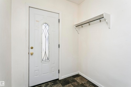 Entryway featuring a white door with decorative glass insert, brass hardware, and contrasting dark flooring - 10035 81 Avenue Nw, Edmonton, AB - Indoor