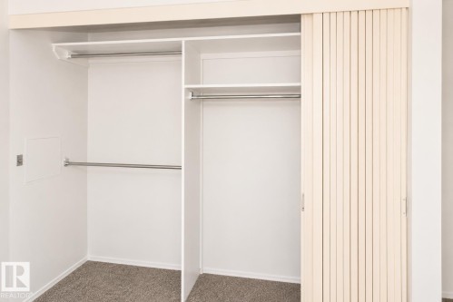 Built-in closet system with multiple rods, shelving, and sliding louvered doors - #223 5125 Riverbend Rd Nw, Edmonton, AB - Indoor