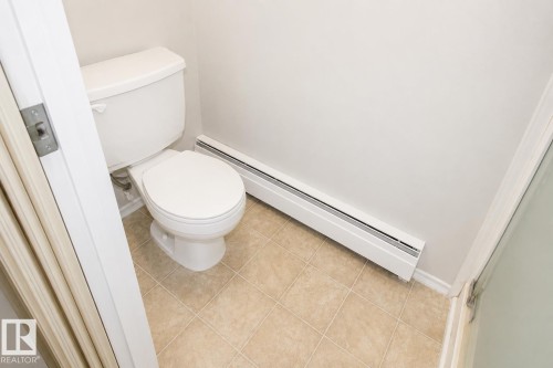 White toilet with a matching tank - #223 5125 Riverbend Rd Nw, Edmonton, AB - Indoor Photo Showing Bathroom
