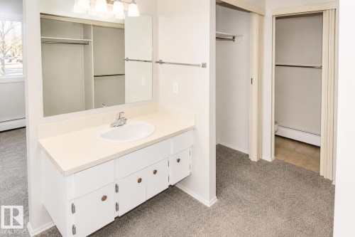 Vanity with integrated sink, wall-mounted mirror, and overhead lighting - #223 5125 Riverbend Rd Nw, Edmonton, AB - Indoor Photo Showing Bathroom