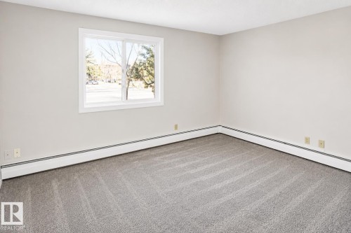 Neutral wall tones, gray carpeting, and white trim window - #223 5125 Riverbend Rd Nw, Edmonton, AB - Indoor Photo Showing Other Room