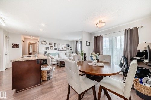 Open-concept living area featuring wood-finish flooring, a kitchen island with stone countertop, recessed lighting, and a sliding glass door with vertical blinds - 311 142 Ebbers Boulevard, Edmonton, AB 