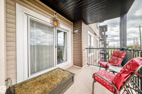 Outdoor balcony featuring a sliding glass door, textured siding, and a black wrought iron railing - 311 142 Ebbers Boulevard, Edmonton, AB 