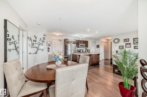 Open-concept living space featuring wood-finish flooring, a dining area, and a kitchen with an island - 311 142 Ebbers Boulevard, Edmonton, AB 