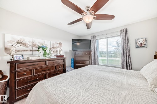 Bright bedroom with a window offering outdoor scenery, featuring a ceiling fan with integrated lighting, and neutral wall tones - 311 142 Ebbers Boulevard, Edmonton, AB 