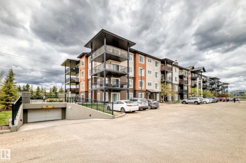 Multi-story residential building with contemporary architecture featuring multiple balconies, a mix of light and dark siding, and an integrated underground parking garage - 311 142 Ebbers Boulevard, Edmonton, AB 