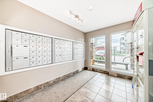 Mail room featuring an extensive wall of individual mailboxes, tile flooring, and large windows providing abundant natural light - 311 142 Ebbers Boulevard, Edmonton, AB 