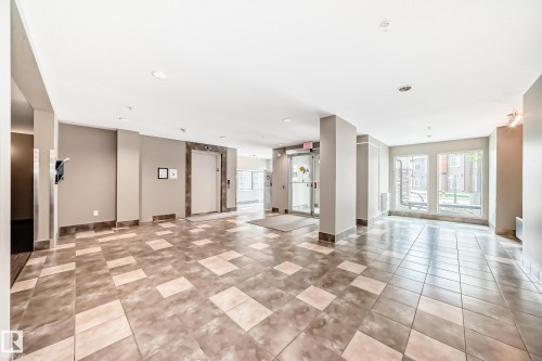 Spacious lobby featuring large square floor tiles, recessed lighting, an elevator with decorative surround, and expansive windows - 311 142 Ebbers Boulevard, Edmonton, AB 