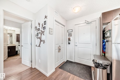 Foyer with wood-finish flooring, white paneled doors, and a flush-mount ceiling light - 311 142 Ebbers Boulevard, Edmonton, AB 