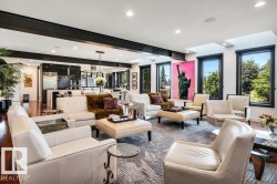 Open-concept living space featuring high ceilings with exposed beams, recessed lighting, and multiple large windows with dark trim - 