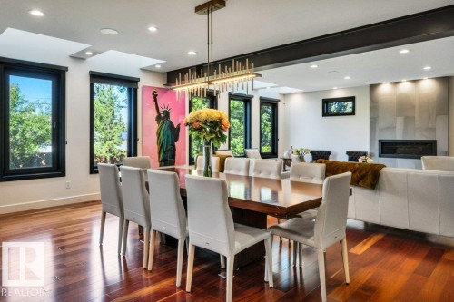 Open-concept living area with lustrous wood-finish flooring, a linear fireplace set into a tile-clad wall, and recessed lighting - 8914 120 Street, Edmonton, AB 