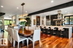 Open-concept living space featuring wood-finish flooring, a long dining table, and a contemporary kitchen - 