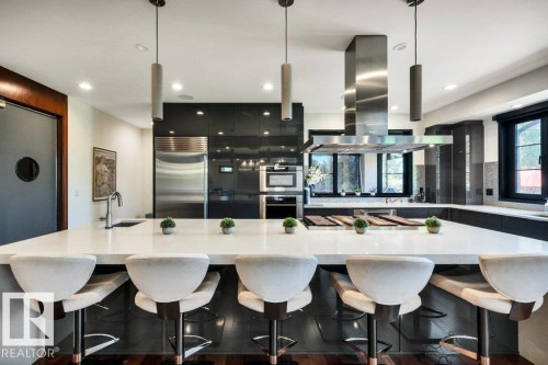 Expansive kitchen island with seating, complemented by dark wood-finish flooring - 8914 120 Street, Edmonton, AB 
