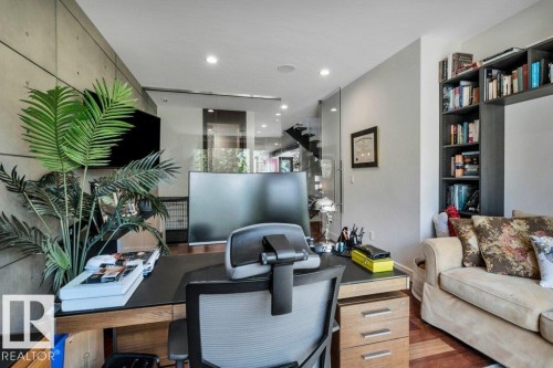 Wood-finish flooring anchors this versatile space, featuring a built-in shelving unit, recessed lighting, and a modern desk area - 8914 120 Street, Edmonton, AB 