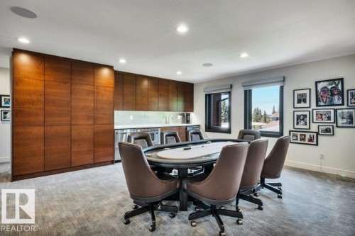 Entertainment room featuring recessed lighting, two windows, wood-finish cabinetry, and a wet bar with a stainless steel undercounter refrigerator - 8914 120 Street, Edmonton, AB 