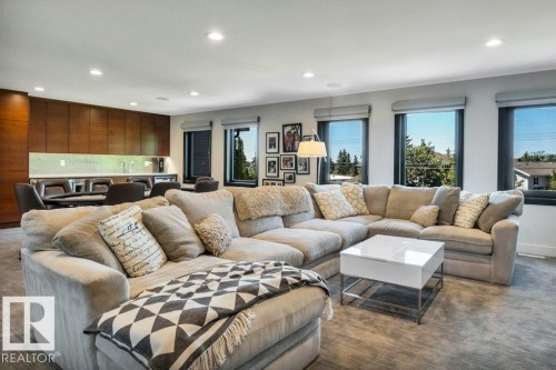 Spacious entertainment area featuring a built-in wet bar with wood-finish cabinetry, recessed lighting, and multiple windows - 8914 120 Street, Edmonton, AB 