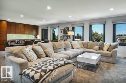 Spacious entertainment area featuring a built-in wet bar with wood-finish cabinetry, recessed lighting, and multiple windows - 