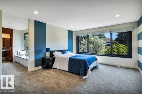 Spacious room featuring multiple windows with tree canopy scenery, recessed lighting, and soft grey textured carpeting - 8914 120 Street, Edmonton, AB 