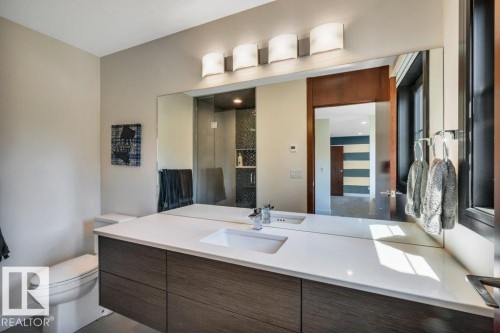 Contemporary bathroom featuring a floating wood-finish vanity with an integrated rectangular sink and a white countertop - 8914 120 Street, Edmonton, AB 
