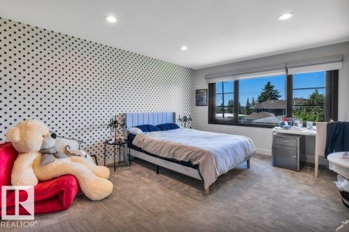 Spacious room featuring a large window with black framing, recessed lighting, and a polka-dot accent wall - 8914 120 Street, Edmonton, AB 