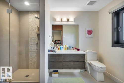 Bathroom with a frameless glass shower enclosure featuring a tiled accent strip and recessed lighting - 8914 120 Street, Edmonton, AB 