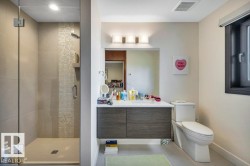 Bathroom with a frameless glass shower enclosure featuring a tiled accent strip and recessed lighting - 
