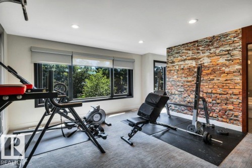 Dedicated fitness space featuring a brick-style accent wall, recessed lighting, and expansive windows - 8914 120 Street, Edmonton, AB 