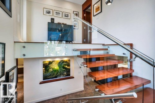 Floating wood-finish staircase featuring a glass and stainless steel railing system - 8914 120 Street, Edmonton, AB 