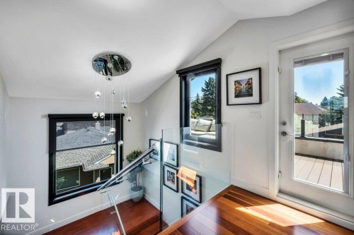 Hardwood flooring extending from a staircase with glass railings - 8914 120 Street, Edmonton, AB 