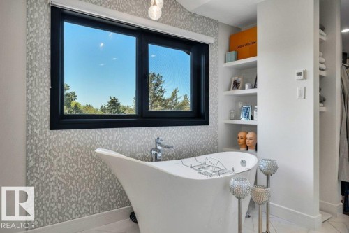 Freestanding soaking tub with chrome fixtures, set against a patterned tile accent wall - 8914 120 Street, Edmonton, AB 