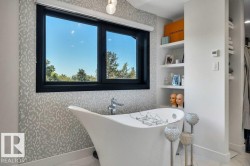 Freestanding soaking tub with chrome fixtures, set against a patterned tile accent wall - 