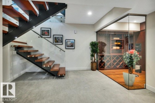 Modern open-tread staircase with wood risers, a black metal stringer, and glass railings - 8914 120 Street, Edmonton, AB 