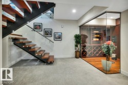 Modern open-tread staircase with wood risers, a black metal stringer, and glass railings - 