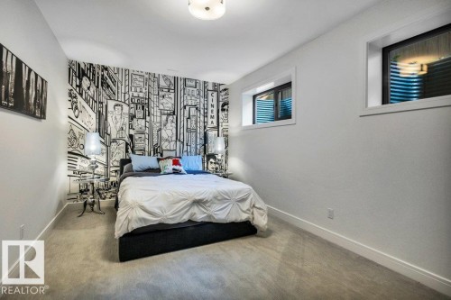 Bedroom featuring a graphic accent wall, neutral carpet flooring, and two transom windows with white trim - 8914 120 Street, Edmonton, AB 