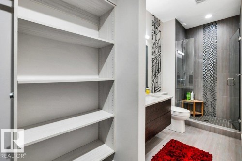 Contemporary bathroom featuring a walk-in shower with mosaic tile detailing, a glass enclosure, and a built-in bench - 8914 120 Street, Edmonton, AB 