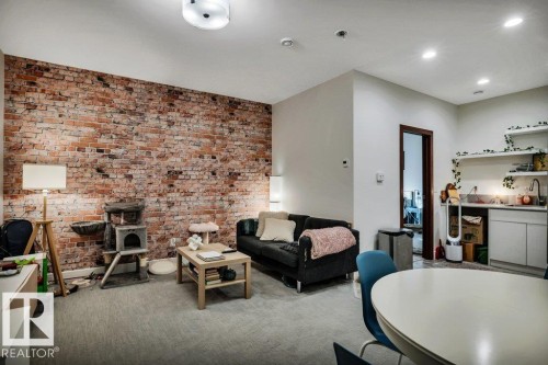 Exposed brick accent wall complementing neutral carpeting - 8914 120 Street, Edmonton, AB 