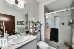Bathroom featuring a single vanity with an oval undermount sink, a large wall-mounted mirror, and a glass-enclosed shower with tiled walls - 