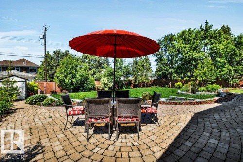 Expansive paver patio with a curved design, surrounded by mature trees and manicured lawn - 8914 120 Street, Edmonton, AB 
