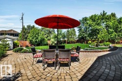 Expansive paver patio with a curved design, surrounded by mature trees and manicured lawn - 