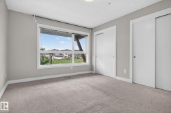 Spacious room featuring a large window, neutral wall paint, and gray carpet flooring - 