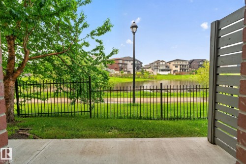 Patio space with concrete flooring, bordered by a black metal fence and green lawn - #90 2560 Pegasus Bv Nw, Edmonton, AB - Outdoor