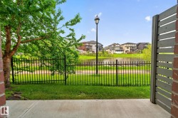 Patio space with concrete flooring, bordered by a black metal fence and green lawn - 