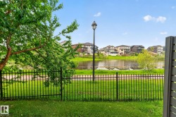 Lakeside property featuring a black wrought iron fence and mature landscaping - 