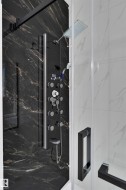 Shower enclosure featuring black marbled tile, a multi-function shower panel, and a square rain showerhead - 