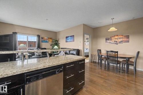 Kitchen island with light-toned countertop and integrated stainless steel dishwasher - 415 263 Macewan Road, Edmonton, AB 