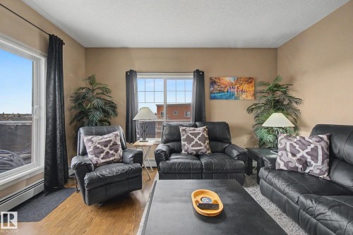 Living area with neutral wall paint, wood-finish flooring, and a large window - 415 263 Macewan Road, Edmonton, AB 