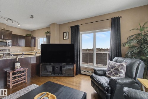 Open-concept living area featuring rich wood-finish flooring - 415 263 Macewan Road, Edmonton, AB 