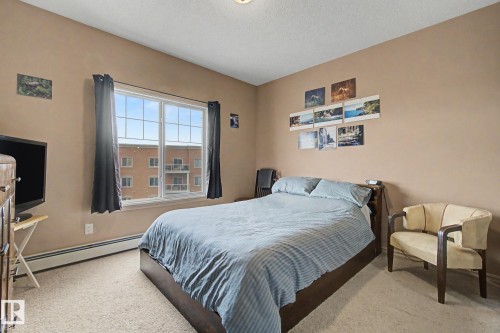 Carpeted room featuring a large window with white framing - 415 263 Macewan Road, Edmonton, AB 